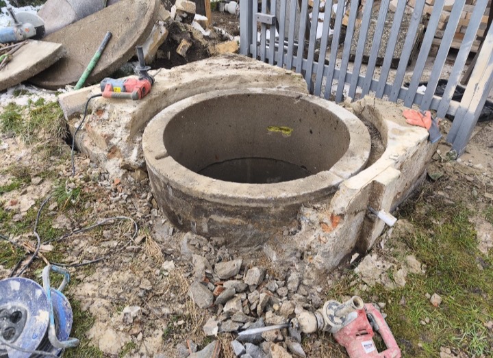 Otevřené záhlaví studny s vybouraným betonovým a cihlovým lemem při opravě