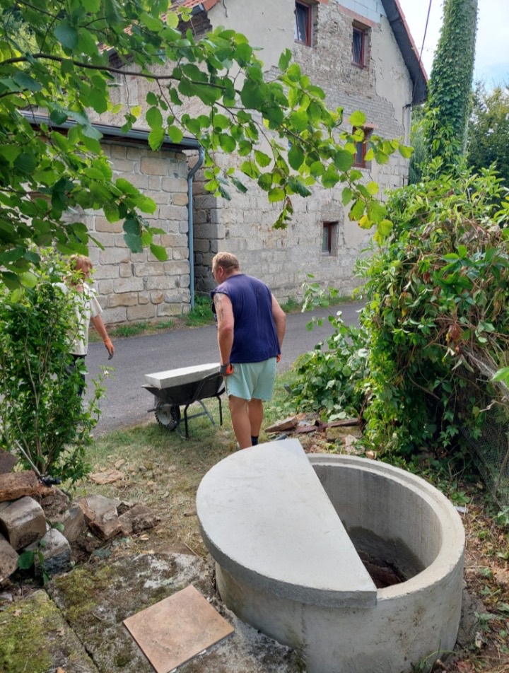 Naši lidé s kolečkem u nově osazené betonové skruže studny na zahradě