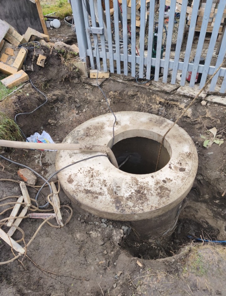 Betonová skruž kopané studny zapuštěná do země, vedle vyvedené kabely